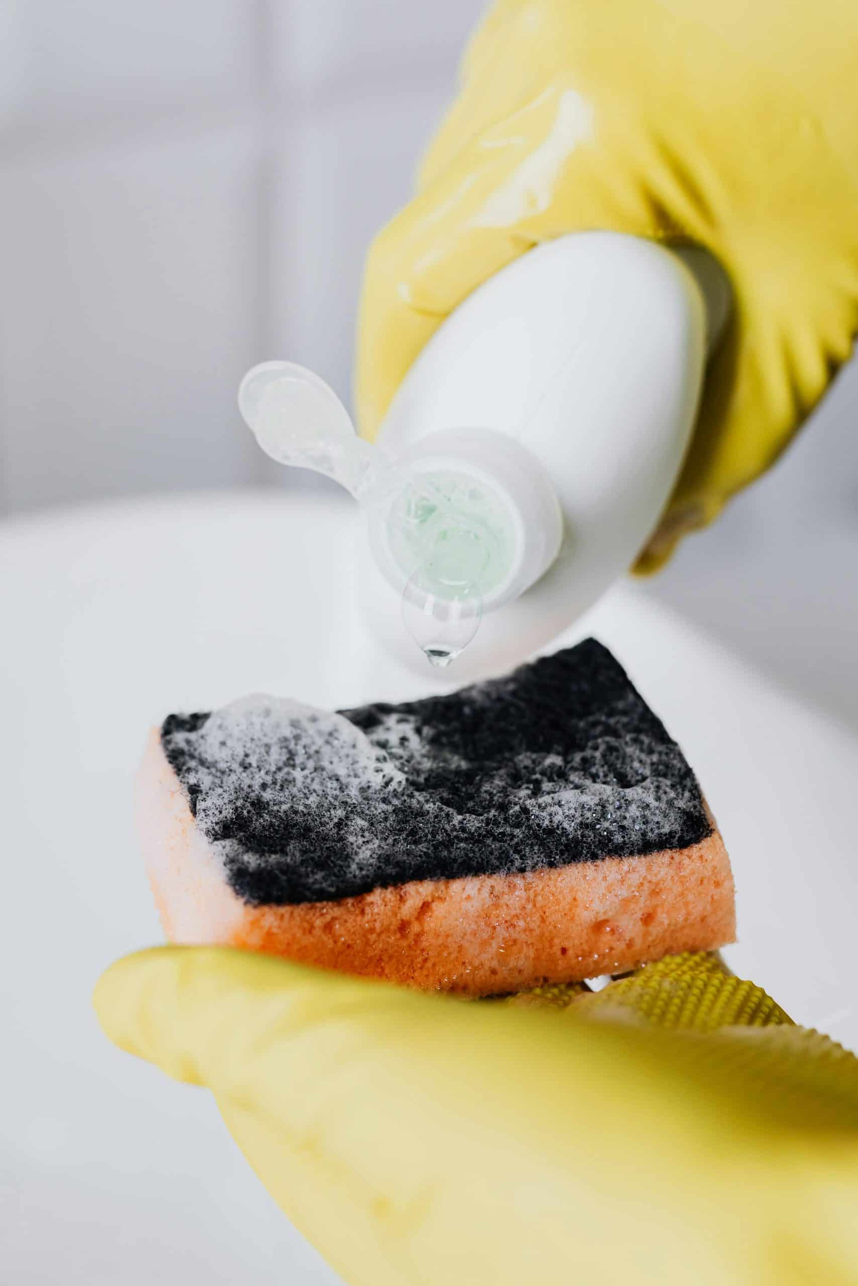 Crop person pouring detergent on sponge